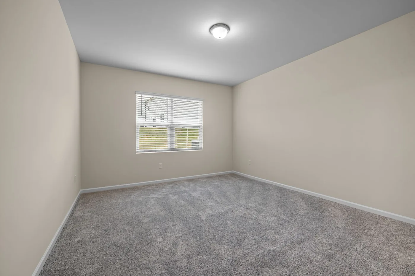Bright empty room with freshly installed carpet and baseboards