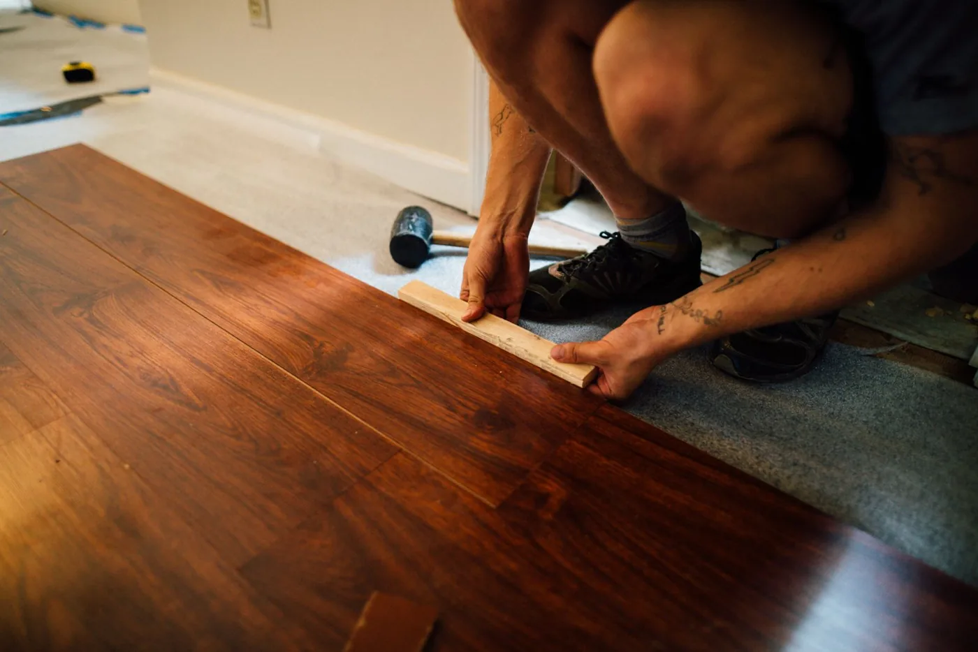 Installer seating a plank row with a tapping block over foam underlayment