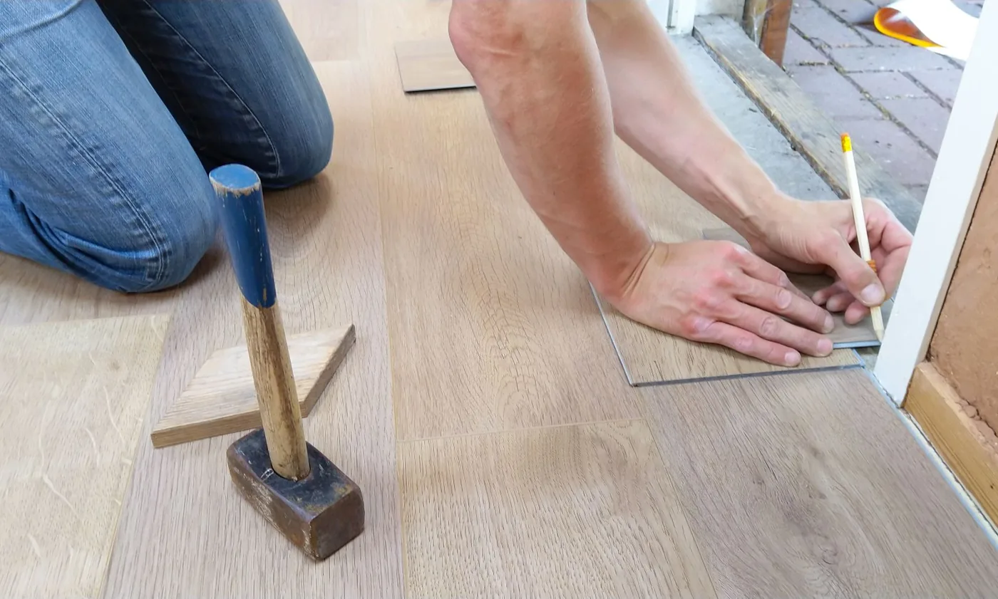 Installer scribing and marking a plank to fit around a door casing