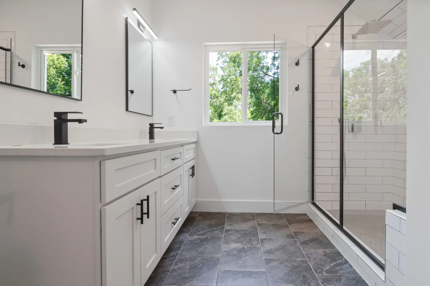 Bathroom with large-format gray tile floor and subway-tiled walk-in shower