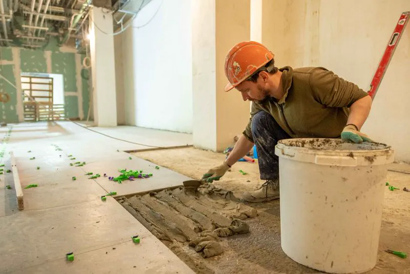 Illustrative example of ceramic tile flooring being set with mortar in a room